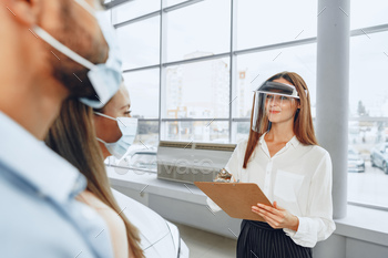 Woman car dealer consulting buyers wearing medical face shield / Photodune, Misc
