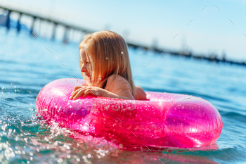 Little girl with pink inflatable circle bathing in sea / Photodune, Misc