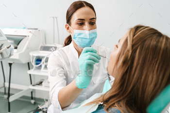 European mid dentist woman in face mask working in dental clinic / Photodune, Misc