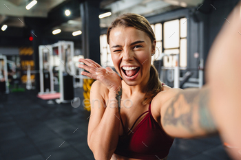 Excited sportswoman holding copyspace and winking while taking selfie / Photodune, Misc