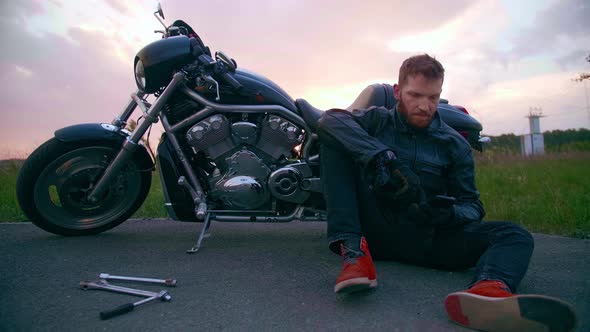 Biker on the Side of the Road with a Broken Chopper Calls to Support