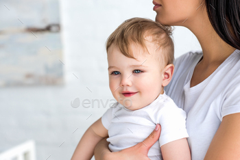 partial view of mother with cute little baby in hands at home / Photodune, Misc