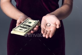 cropped shot of woman holding stack of cash and wedding ring, marriage of convenience concept / Photodune, Misc