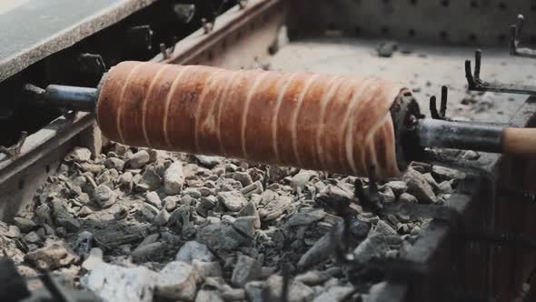 Making a hungarian chimney cake above the glowing ember.