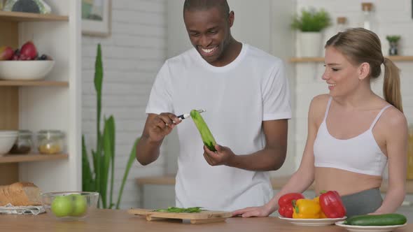 Athletic Couple Peeling Cucumber in Kitchen