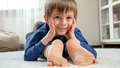 Portrait of happy smiling boy lying on mother's feet and looking in camera. Family having fun - PhotoDune Item for Sale