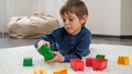 Cute little boy lying on soft carpet and playing with colorful toy blocks. Concept of child - PhotoDune Item for Sale