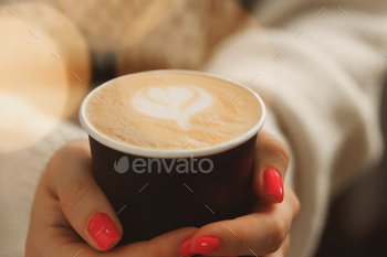 Female hands in sweater holding a cup of latte coffee / Photodune, Misc