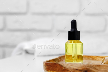 Bottle of yellow cosmetic oil on wooden tray close up / Photodune, Misc
