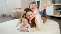 Happy smiling and laughing family with children relaxing on carpet in living room. Parenting - PhotoDune Item for Sale