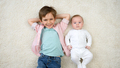 Cute little baby boy with older brother lying on carpet and smiling in camera. Children happiness - PhotoDune Item for Sale