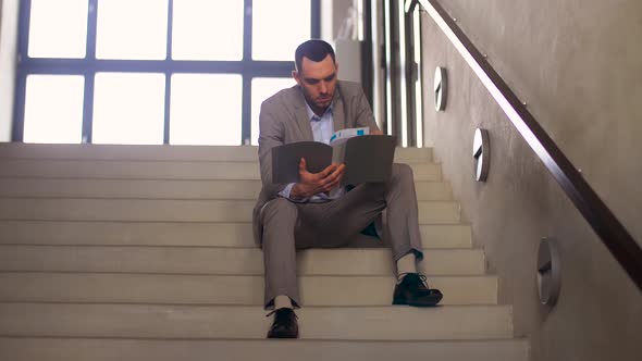 Businessman with Folder Sitting on Stairs 33