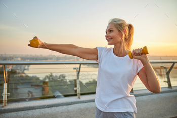 Woman performing a strength training exercise outdoors / Photodune, Misc