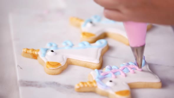 Step by step. Decorating unicorn shaped sugar cookies with royal icing for little girl birthday part