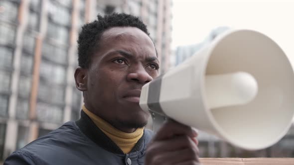 Closeup African American Man Shouts Angrily with Megaphone and Holds a Sign Black Lives Matter