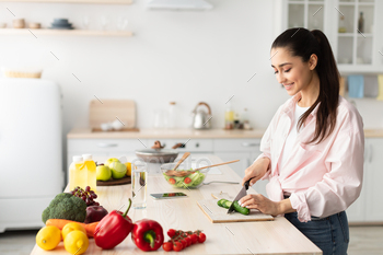 Portrait of smiling young lady cooking fresh salad / Photodune, Misc