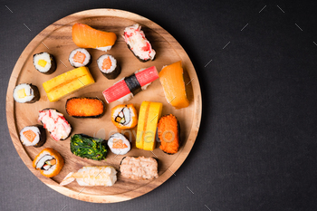 Top view of Sushi set on wooden plate on black background, Japanese food. Free space for text / Photodune, Misc