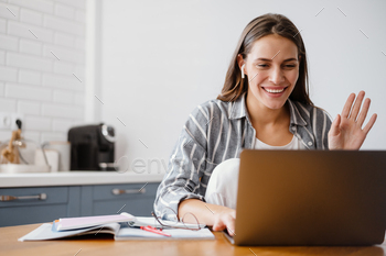 Cheerful beautiful woman waving hand while making online call on laptop / Photodune, Misc