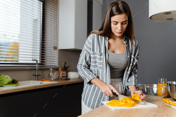 Charming focused woman preparing salad in cozy kitchen at home / Photodune, Misc