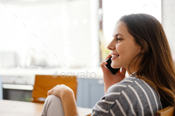 テーブルに座って携帯電話で話している幸せな女性 / Photodune, Misc