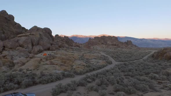 Aerial shot of a young man backpacker camping with his dog in a mountainous desert.