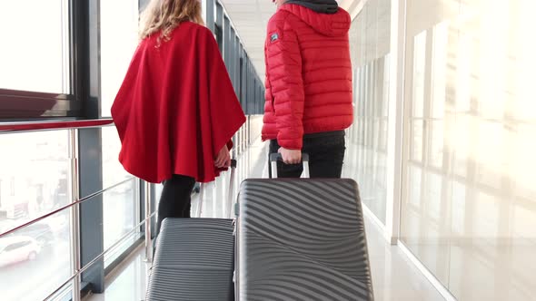 Couple in Red Clothing with Suitcases Going for Flight