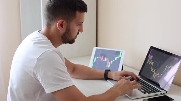 Man Looking at Finance Chart on Laptop and Tablet Day Trader Investing From Home