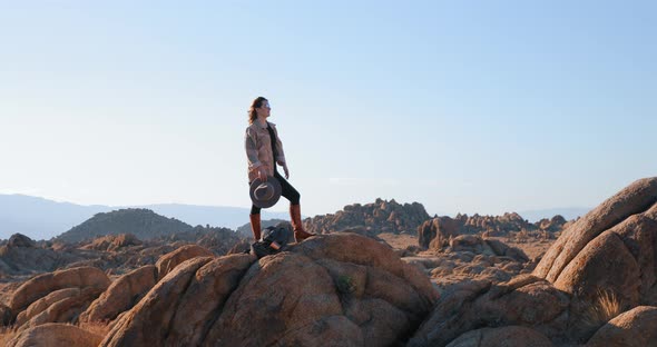 Young Independent Woman on a Rocky Peak Looking at Nature Landscape at Sunrise