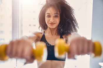 Positive delighted female person lifting yellow dumbbells / Photodune, Misc