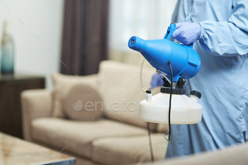 Worker wearing protective overalls while disinfecting a hotel apartment