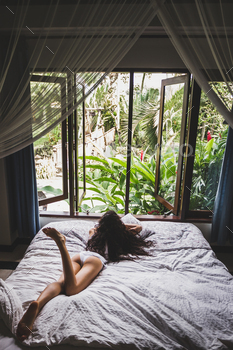 Woman in white lingerie lounging in bed in the morning, view from window on tropical garden / Photodune, Misc