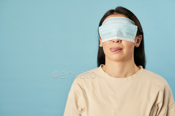  protective mask on her eyes on a blue background. Copy space. Quarantine, epidemic concept