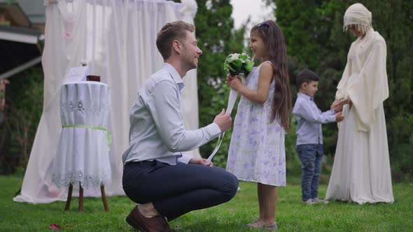 Side View Portrait of Caucasian Young Man Giving Wedding Bouquet to Charming Middle Eastern Flower