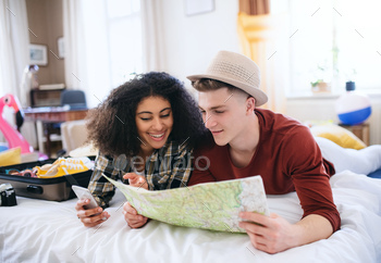 Cheerful young couple preparing and packing for summer holiday at home, planning / Photodune, Misc