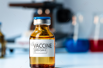 Vial of Covid-19 vaccine next to a microscope / Photodune, Misc