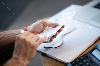 Close up of businessman holding bills while studying expenses / Photodune, Misc