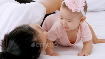 Young mother with her little baby playing on bed at home. / Photodune, Misc