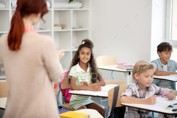 Girl wearing striped dress looking at teacher / Photodune, Misc
