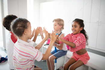 Boys and girls clapping their hands while sitting in locker room / Photodune, Misc