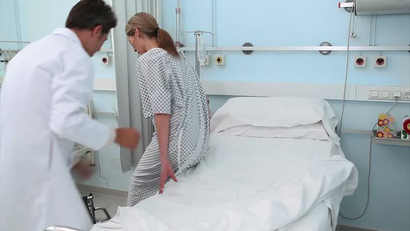 Doctor assisting a patient to lie on a bed