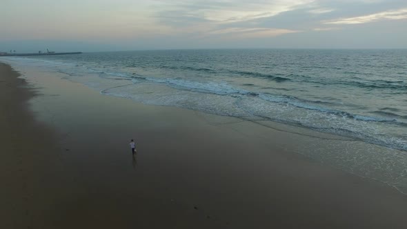 Aerial shot of little boy playing soccer on the beach at sunset.