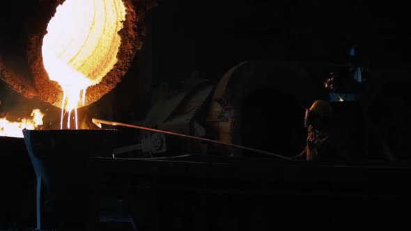 Worker Pouring Molten Metal From Ladle In Foundry Workshop.