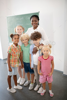 Loving smiling teacher hugging her cute smart pupils / Photodune, Misc
