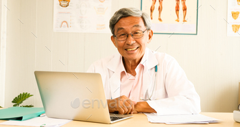 Asian doctor smiling and sitting at doctor's room. / Photodune, Misc