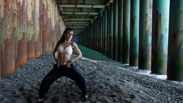 Freedom Loving Woman is Dancing Under Pier Moving on Pebble Sea Beach