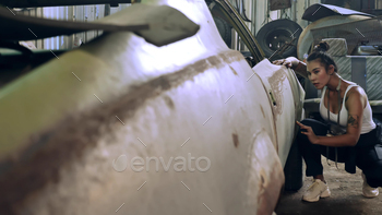 Attractive young woman mechanical worker repairing a vintage car in old garage. / Photodune, Misc