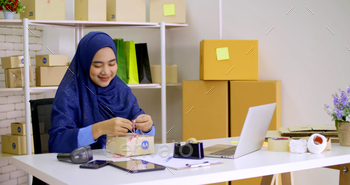 Beautiful muslim female merchandiser preparing parcel at the office. / Photodune, Misc