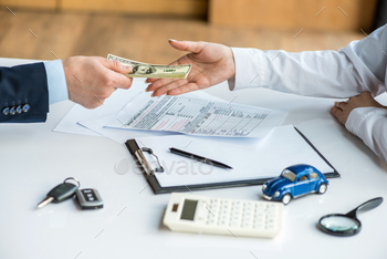 cropped view of man and woman holding dollar banknotes near toy car, clipboard, keys, calculator, / Photodune, Misc