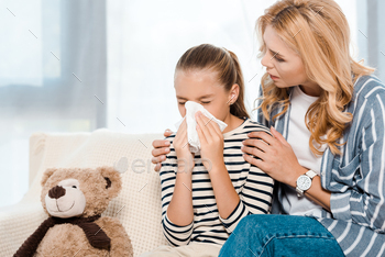 woman sitting near daughter sneezing in tissue near teddy bear / Photodune, Misc