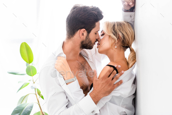 Side view of businessman kissing sexy colleague by wall in office / Photodune, Misc